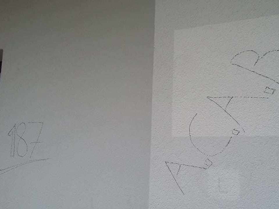 Eine Zahl und vier Buchstaben auf einer Hausmauer
