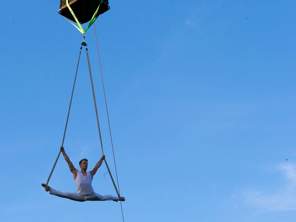 Mann hängt an Heissluftballon macht Akrobatik 