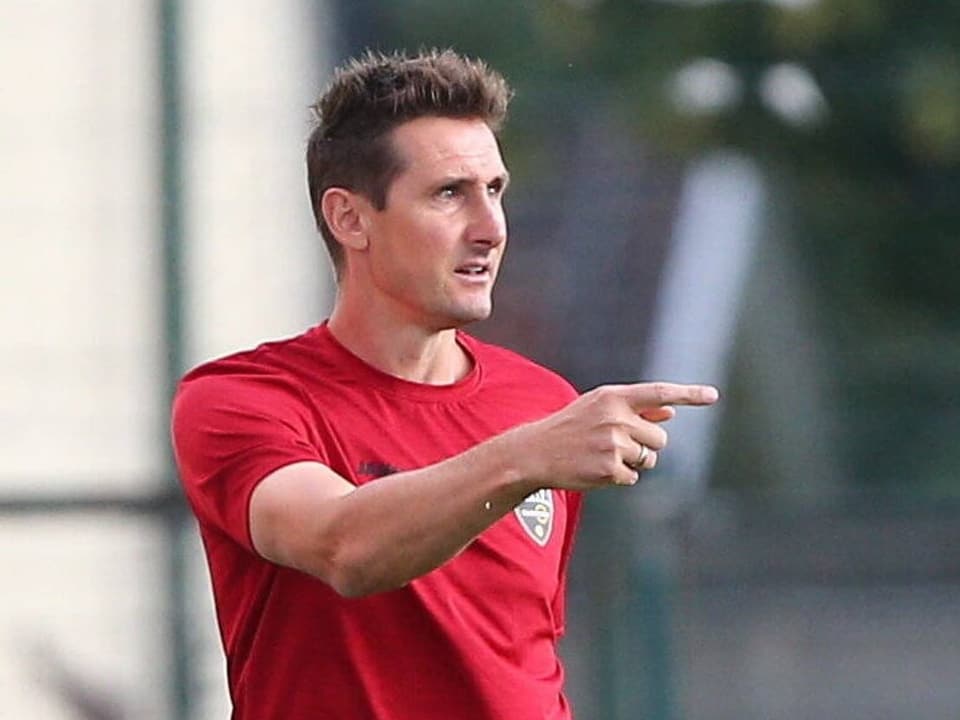 Miroslav Klose zeigt mit dem Finger auf den Fussballplatz.