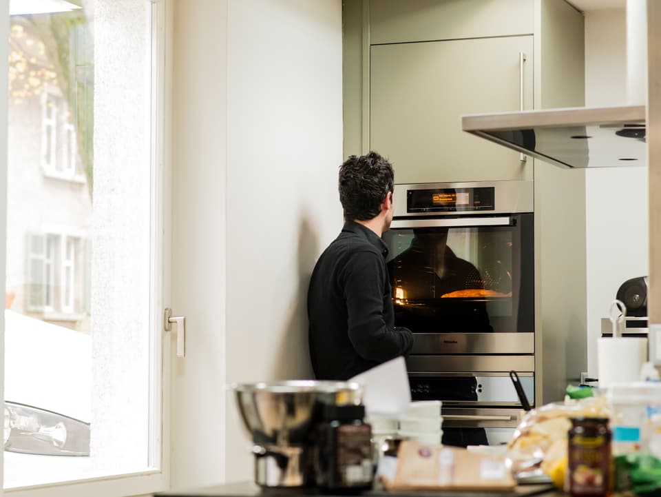 Zu sehen ist Philippe Gerber, wie er vor dem Backofen wartet und den Grittibänzen im Ofen anguckt.