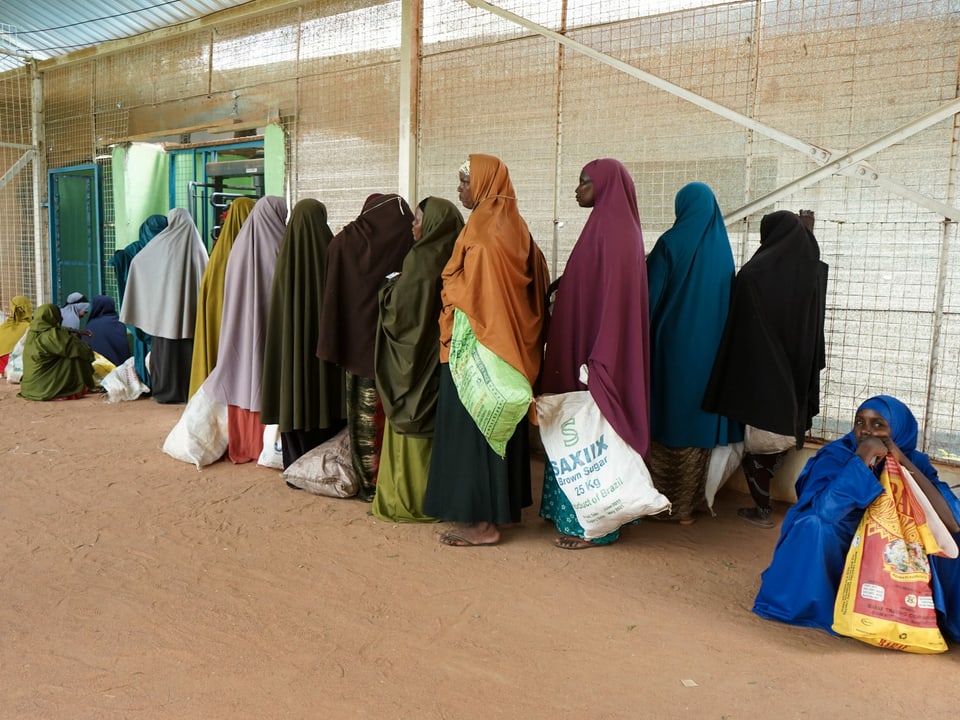 Frauen in bunten Kleidern und Kopftüchern bilden im Lager Dadaab in Kenia eine Schlange vor der Essensausgabe der WFP.