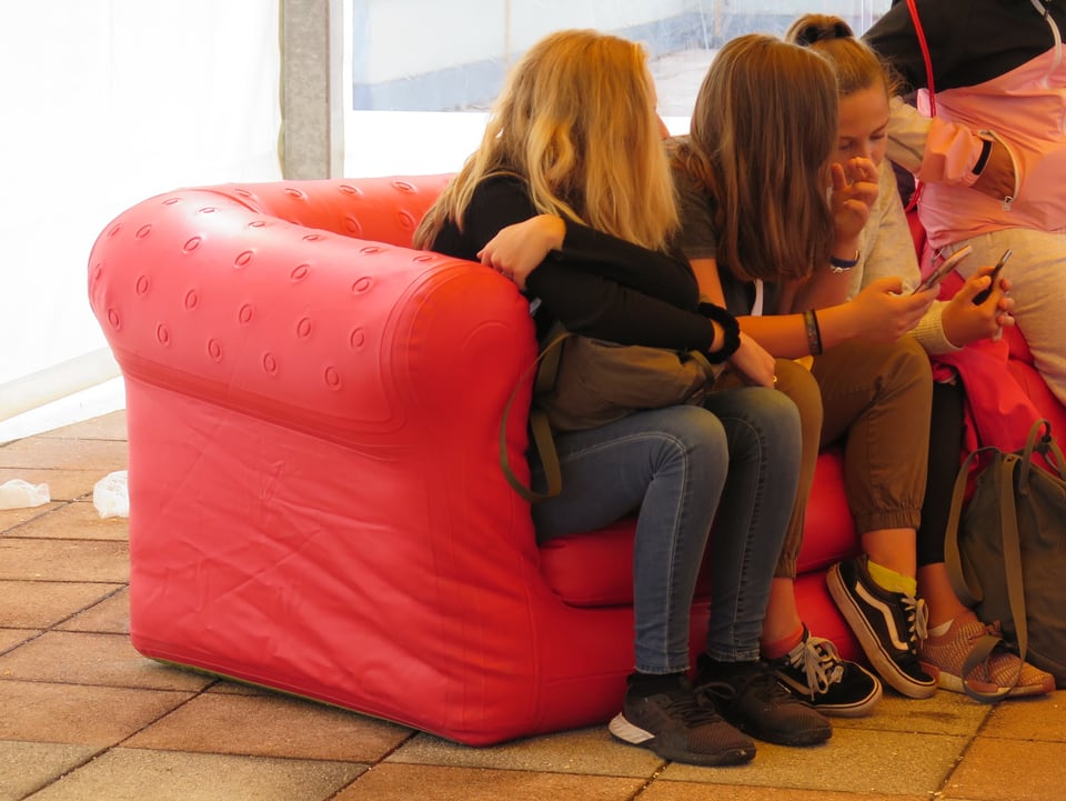 Mädchen sitzen auf rotem Sofa