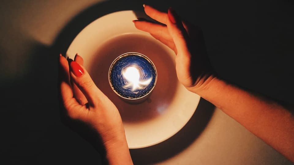 Kerze und zwei Frauenhände.