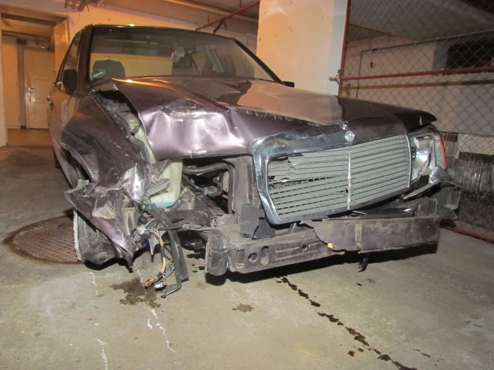 Der stark zerstörte Mercedes in einer Garage, davor eine Ölspur.