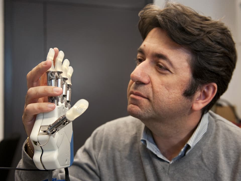 Silvestro Micera hält den Prototyp der neuen Hand-Prothese der EPFL in der Hand.