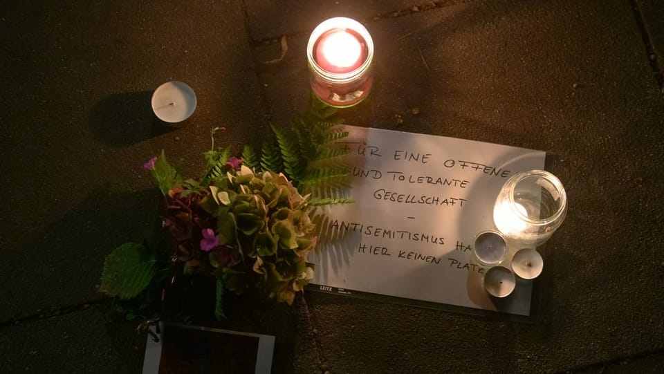Blumen und Kerzen und ein Zettel mit dem Titel "Für eine offene Gesellschaft" liegen Nahe der Hamburgert Synagoge am Boden