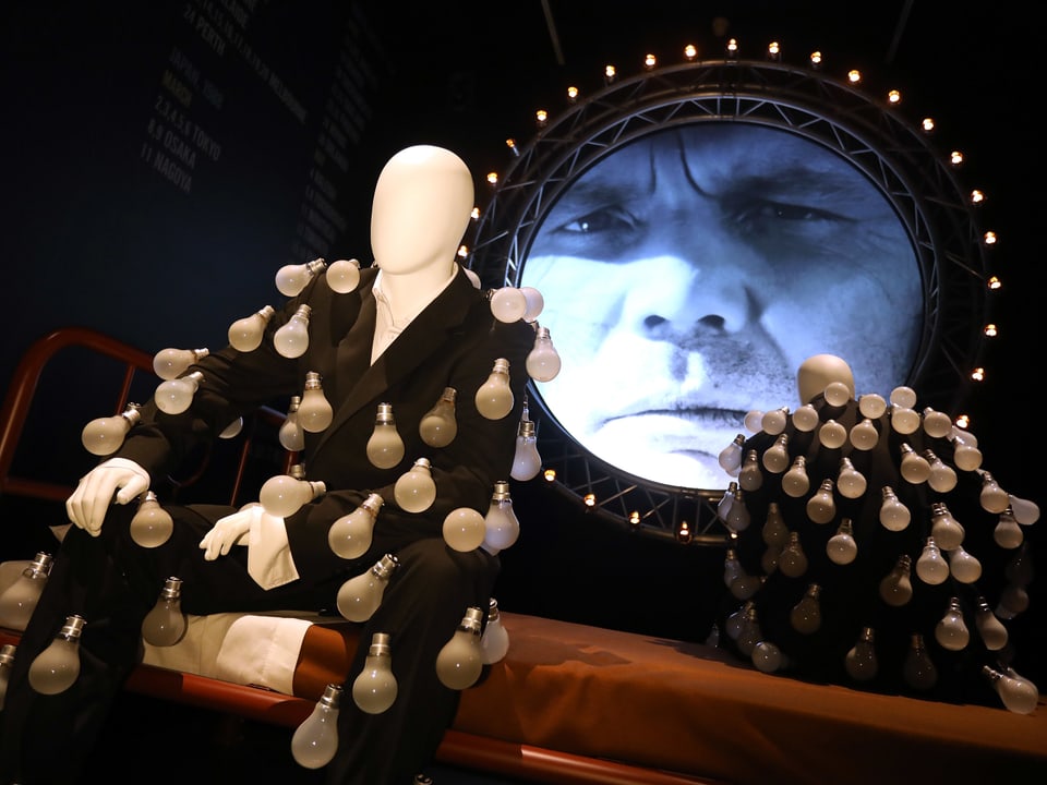 Im Londoner Museum: Eine Figur im Anzug, auf dem Glühbirnen montiert sind.
