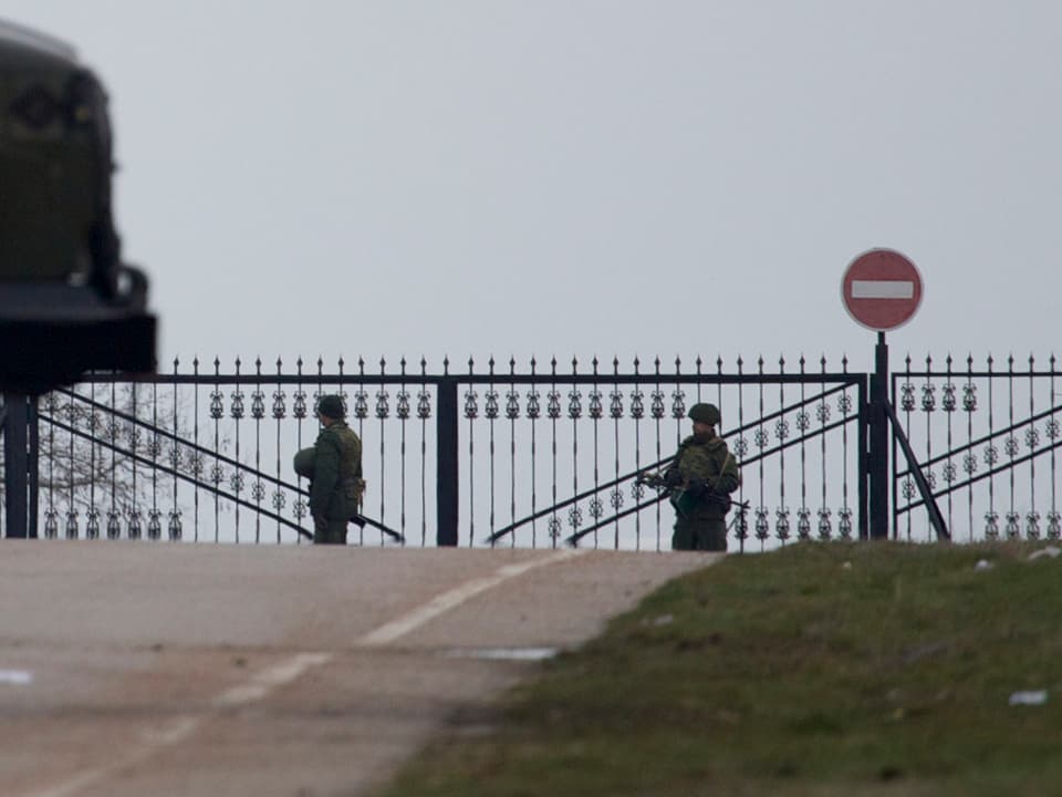 Zwei militärisch gekleidete Männer bewachen den Eingang zum Militärflughafen im Hafen von Sewastopol. 