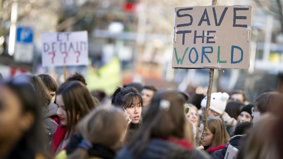 Gruppe von Jugendlichen. Auf einem Plakat steht: Save the World.