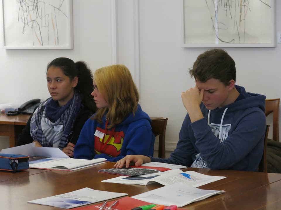 Drei Jugendliche mit Unterlagen vor sich sitzen am Sitzungstisch