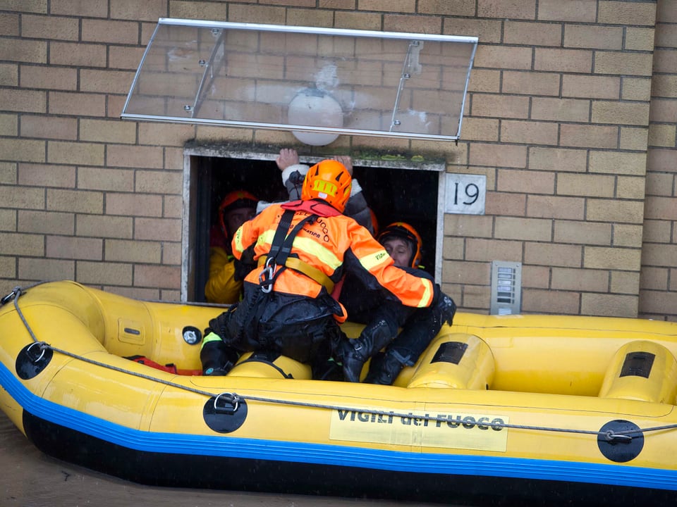 Italienischer Feuerwehrmann in einem Schlauchboot vor einem Kellerfenster