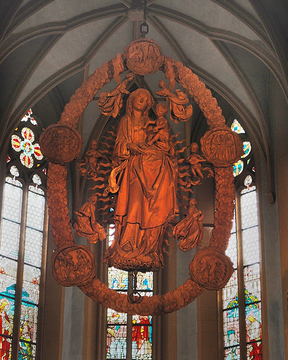 Holzskulptur, die in einem Kirchenraum hängt.