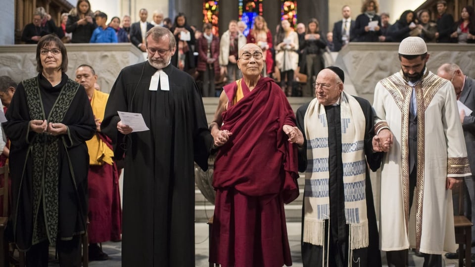 Fünf Geistliche verschiedener Religionen stehen nebeneinander in einer Kirche. 