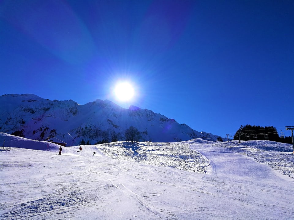 Skifahrer auf einer glatten Pisten, es herrscht Sonnenschein.