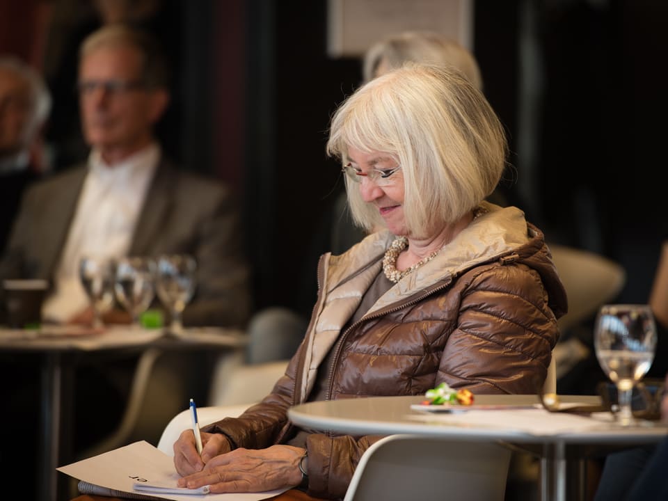 Eine Frau sitzt an einem Tisch und macht Notizen.