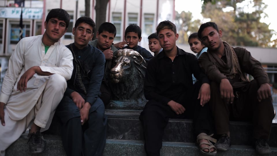 Junge Männer mit Bronzestatue eines Löwen.