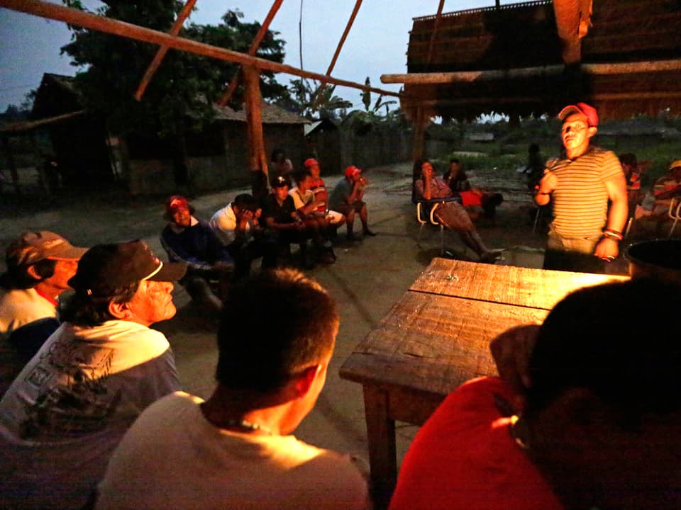 Junge Krieger der Ka'apor-Indianer im brasilianischen Bundesstaat Maranhão sitzen im Licht einer Petroleumlampe um einen Kartentisch herum und beraten die nächste Aktion im Wald.