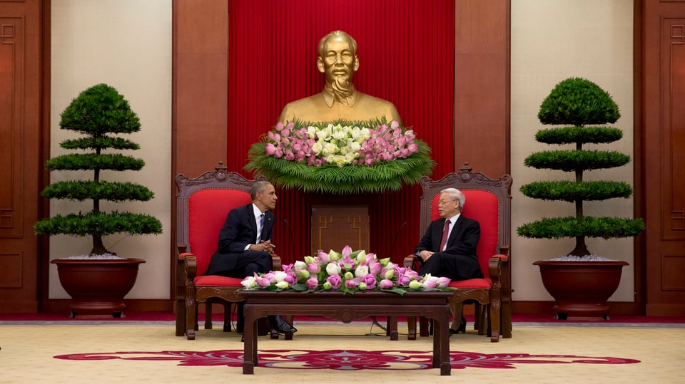 Die beiden Politiker sitzen an einem mit Blumen geschmückten Tisch.