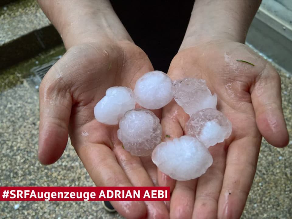 Zwei Hände voll mit baumnussgrossen Hagelkörnern.