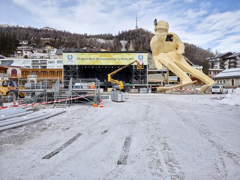 19 Meter hohe hölzerne Ski-Figur vor einer grossen Bühne in St. Moritz.
