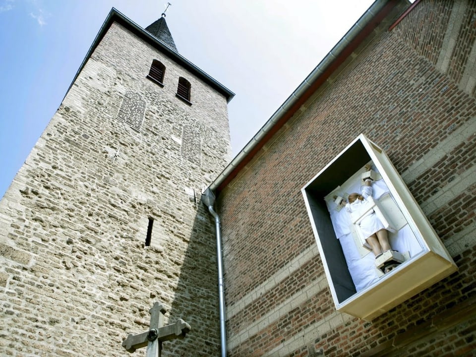 ein gekreuzigte Frau hängt an einer Kirchenfassade