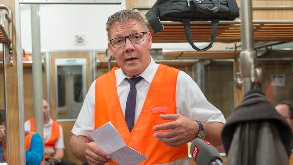 Mann mit orangem Gilet in altem Zug