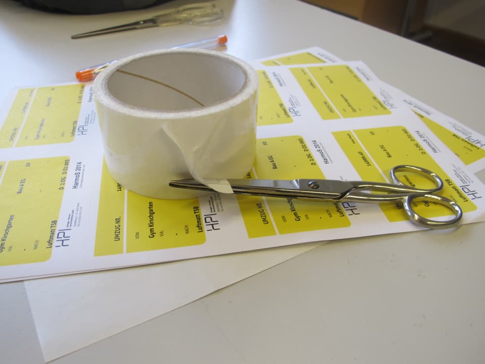 Schere und Klebstreifen, mit gelben Zetteln um das Umzugsgut anzuschreiben. 