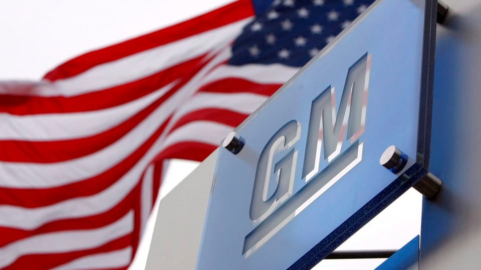 Ein Logo von GM neben einer US-Flagge.