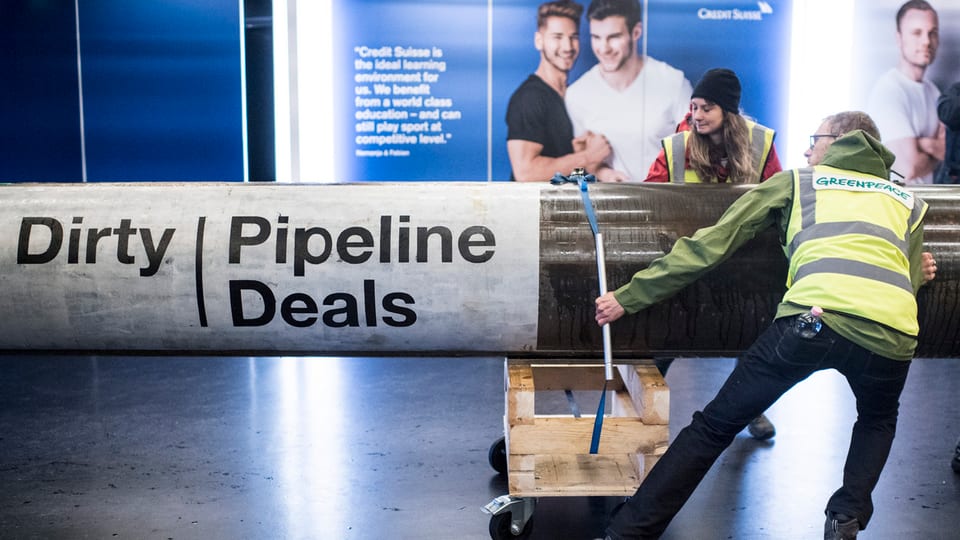 Zwei Greenpeace-Aktivisten rollen eine Pipeline ins Foyer des Hallenstadions