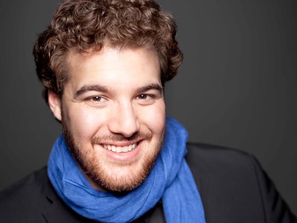 Der Sänger Mauro Peter lächelt und trägt einen Schal um den Hals.