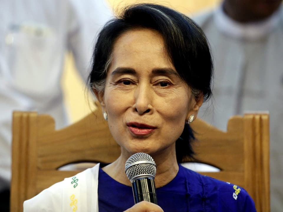 Aung San Suu Kyi sitzt auf einem Stuhl und spricht in ein Mikrophon