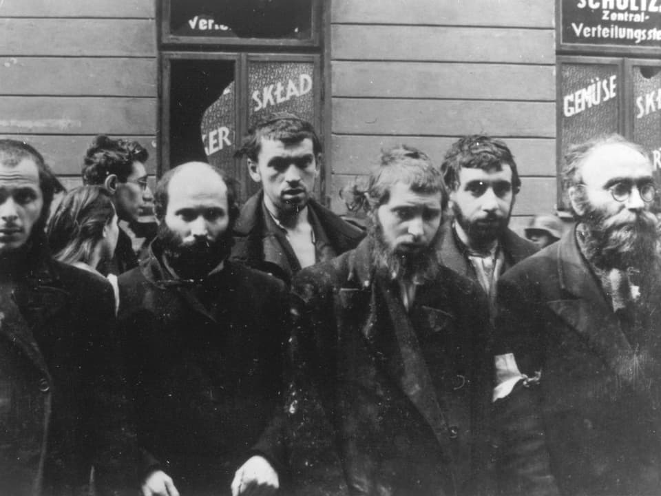 Schwarz-Weiss-Bild: Juden stehen in Reih und Glied bereit zum Abtransport.