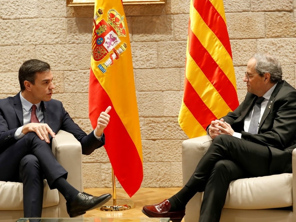 Pedro Sánchez (links) und Quim Torra (rechts) sitzen nebeneinander vor den Fahnen Spaniens und Kataloniens.