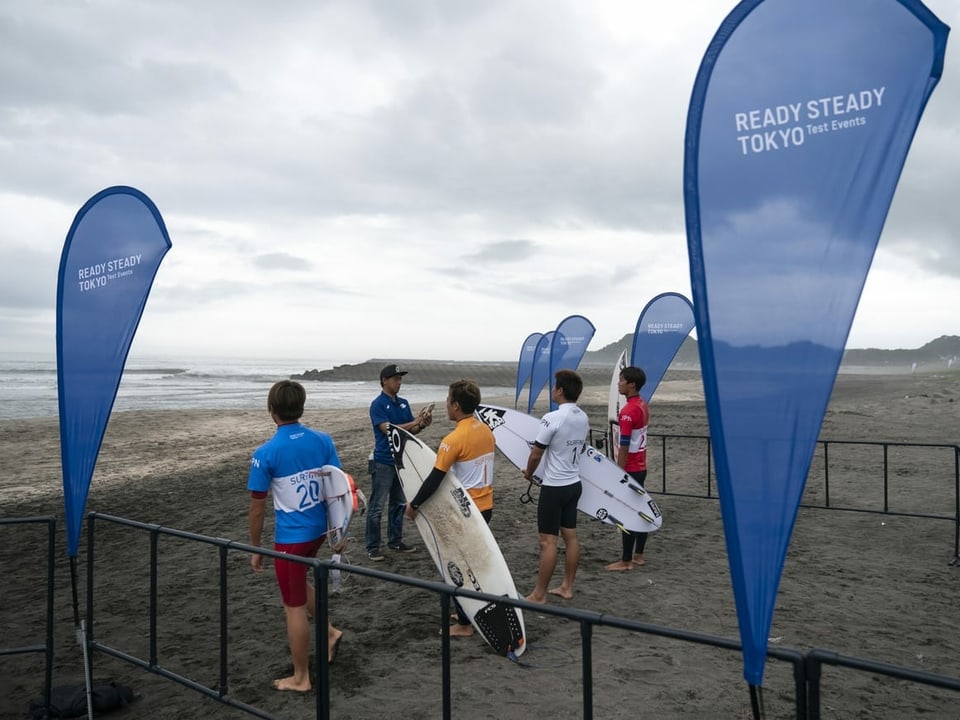 Surfer stehen am Strand der Olympiade in Tokio.