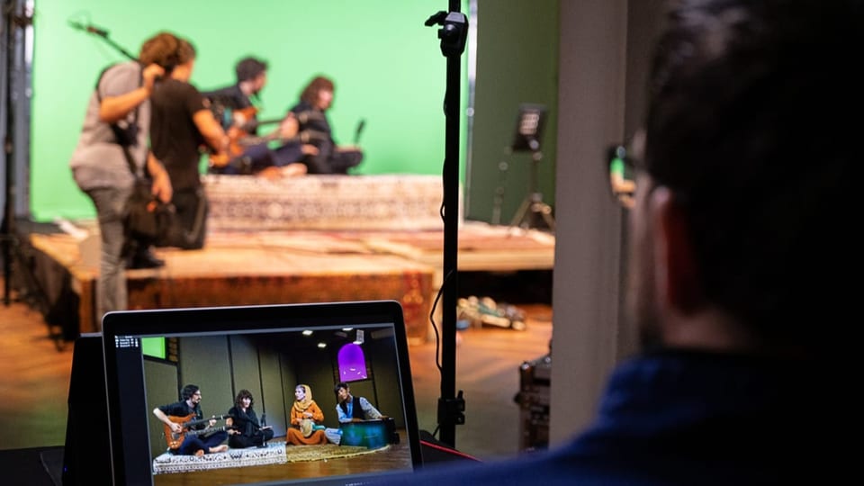 Musiker sitzen vor einem Greenscreen und werden gefilmt.