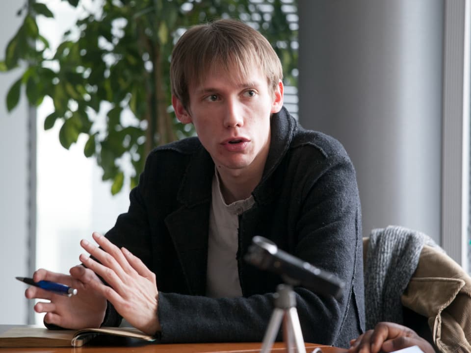 Grigory Okhotin sitzt auf einem Tisch.