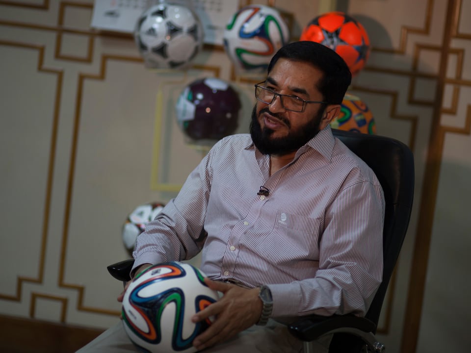 Firmeninhaber Khawaja Masood Akhtar sitzt mit Ball in der Hand da