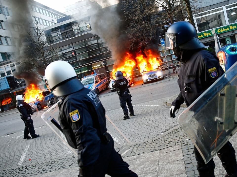 Polizisten stehen vor brennenden Polizeiwagen in Frankfurt am Main. (reuters)