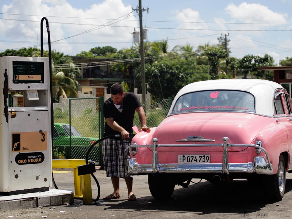 Ein Mann tankt sein altes Auto auf Kuba.