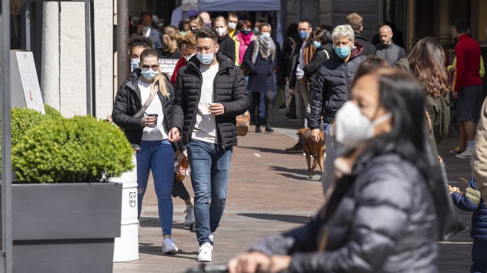 Menschen mit Masken in einer Strasse.