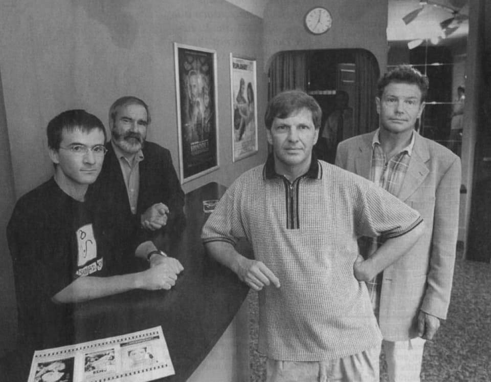 A black and white picture shows four men in the entrance area of ​​a cinema.