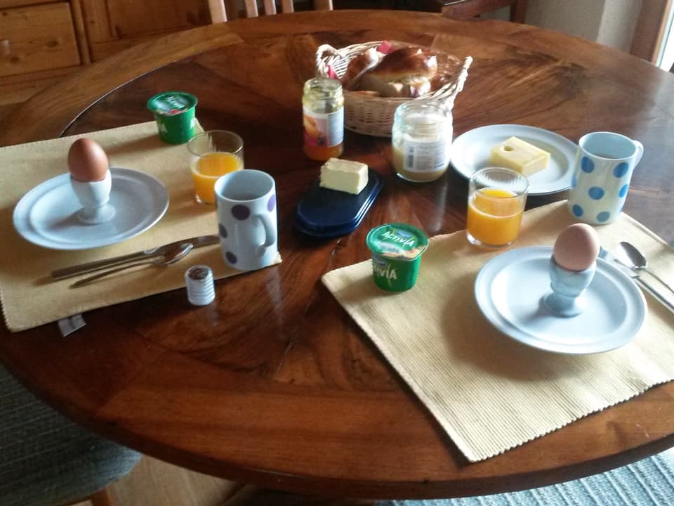 Frühstück mit Ei, Orangensaft, Butter, Konfitüre, Yoghurt, Honig.