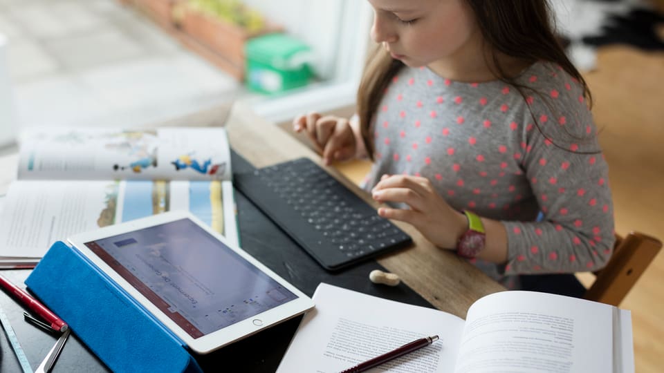 Ein Mädchen macht Hausaufgaben an einem Tablet.