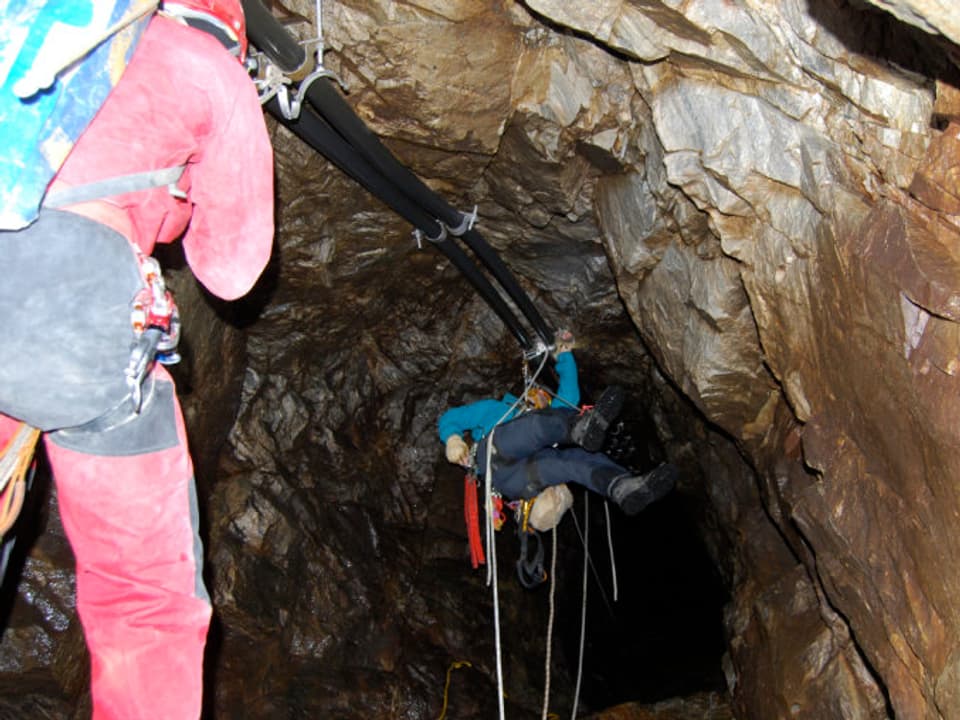 Zwei Bergsteiger hangen an der Decke eines kleinen Felsen-Tunnels