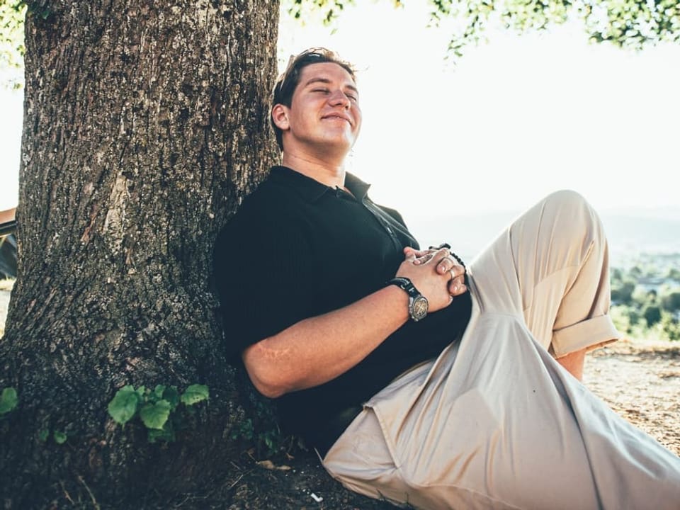 Marius Baer chillt an einem Baum