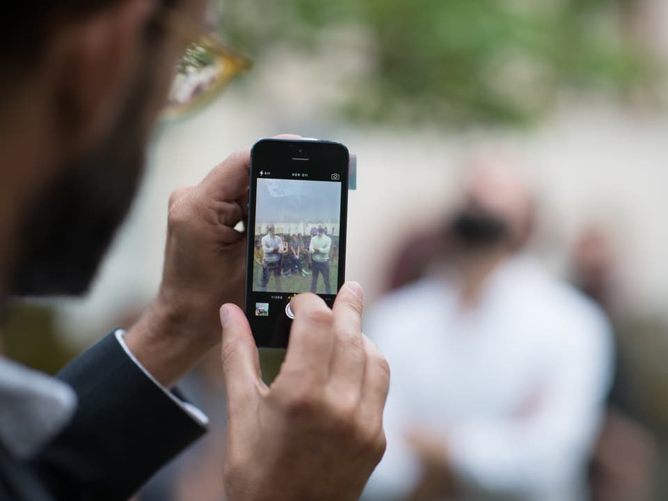 Ein Mann fotografiert mit einem Smartphone eine Performance.