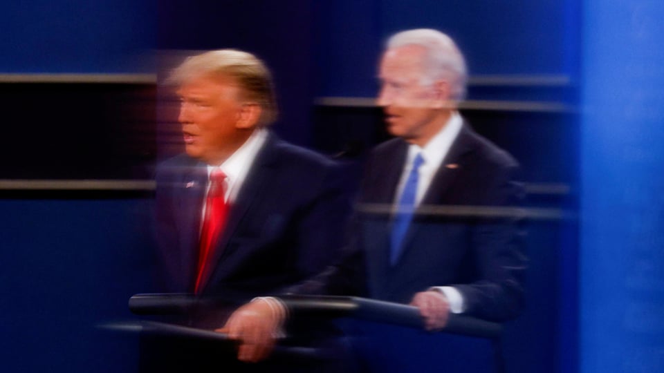 Donald Trump und Joe Biden spiegeln sich in einem Plexiglas.