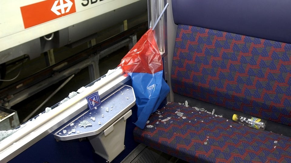 Eine eingeschlagene Scheibe, dreck auf der Sitzbank, eine blauweisse Plastikflagge.