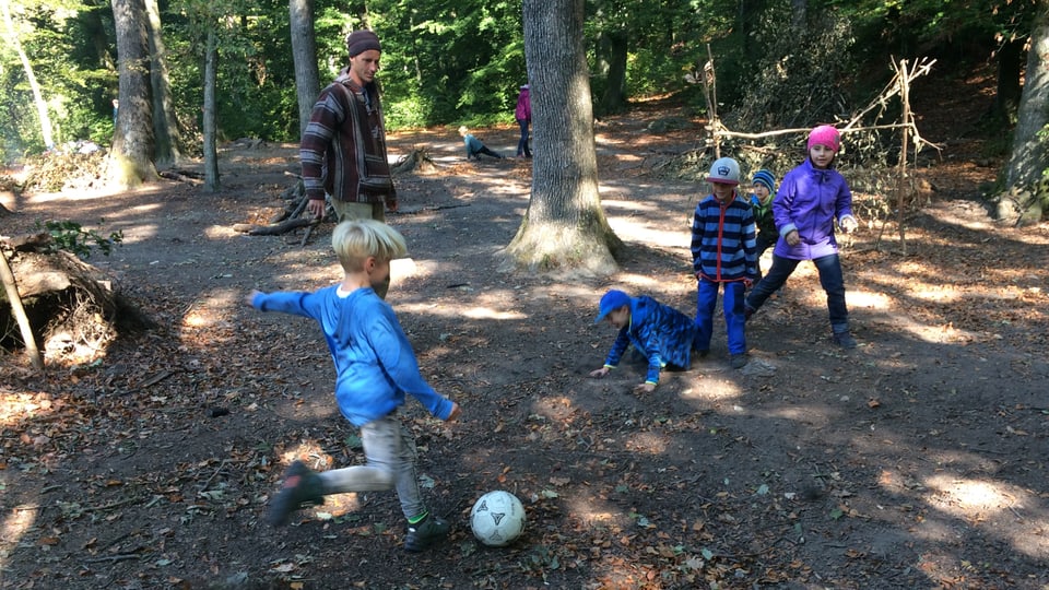Kinder spielen im Wald Fussball.