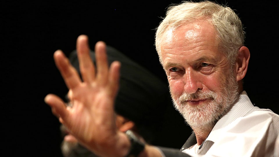 Labour-Kandidat Jeremy Corbyn am Rednerpult, streckt stoppend den Arm vor.